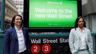 Robinhood CEO and co-founder Vlad Tenev and co-founder Baiju Bhatt pose with Robinhood signage on Wall Street after the company’s initial public offering in New York City, July 29, 2021.