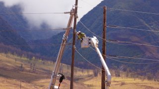 Electrical workers repair power lines leading into the fire ravaged town of Lahaina on the island of Maui in Hawaii, August 15, 2023.