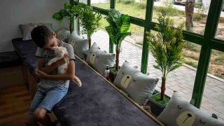 A Palestinian child enjoys the company of a cat on the opening day of Meow Cafe, Gaza City, Aug 17, 2023.