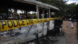 FILE - A police officer walks beside a burnt prison vehicle in Abuja, Nigeria on July 6, 2022, after suspected Boko Haram gunmen attacked the Kuje Medium Prison.