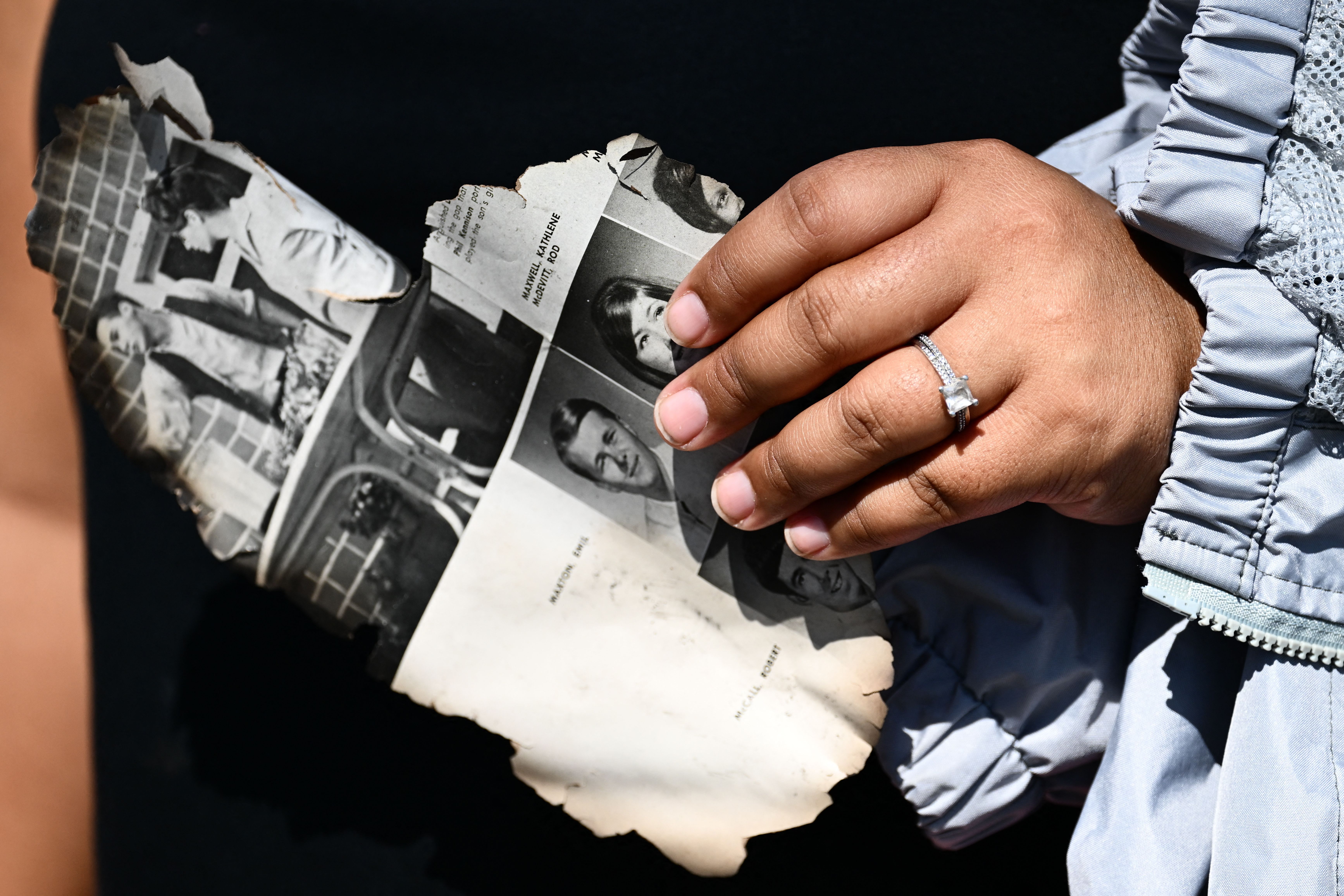 Davilynn Severson holds a page of a yearbook as she looks for belongings through the ashes of their family’s home in the aftermath of a wildfire in Lahaina, Maui, Hawaii, Aug. 11, 2023.