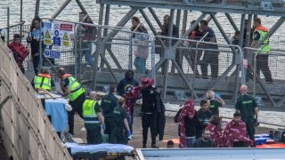 Paramedics wait to tend to assist migrants picked up at sea while attempting to cross the English Channel