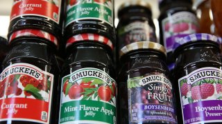 Smuckers fruit products are displayed on a shelf at a grocery store.