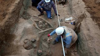 Archaeologists uncover bones and vessels discovered by city workers who were digging a natural gas line for the company Calidda in the district of Carabayllo on the outskirts of Lima, Peru, Friday, Sept. 22, 2023.