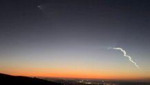 The sunset glows as a rocket streaks across the sky from Vandenberg Air Force base on SEpt. 14, 2023.