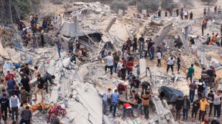 Civilians and rescuers look for survivors amid the rubble of a destroyed building following an Israeli bombardment in Khan Younis in the southern Gaza Strip on November 12, 2023.