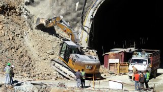 A heavy machinery works at the the entrance to the site of an under-construction road tunnel that collapsed in mountainous Uttarakhand state, India