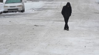 A person crosses a snow covered street Thursday, Jan. 18, 2024, in Nashville, Tenn.