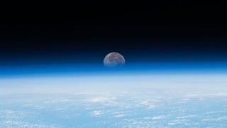 The moon appears beyond Earth’s horizon as seen from the International Space Station on Nov. 30, 2023.