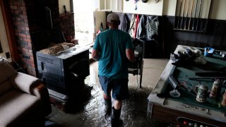 A Johnson, Vermont, resident removes items destroyed in flooding of a finished basement in 2023.