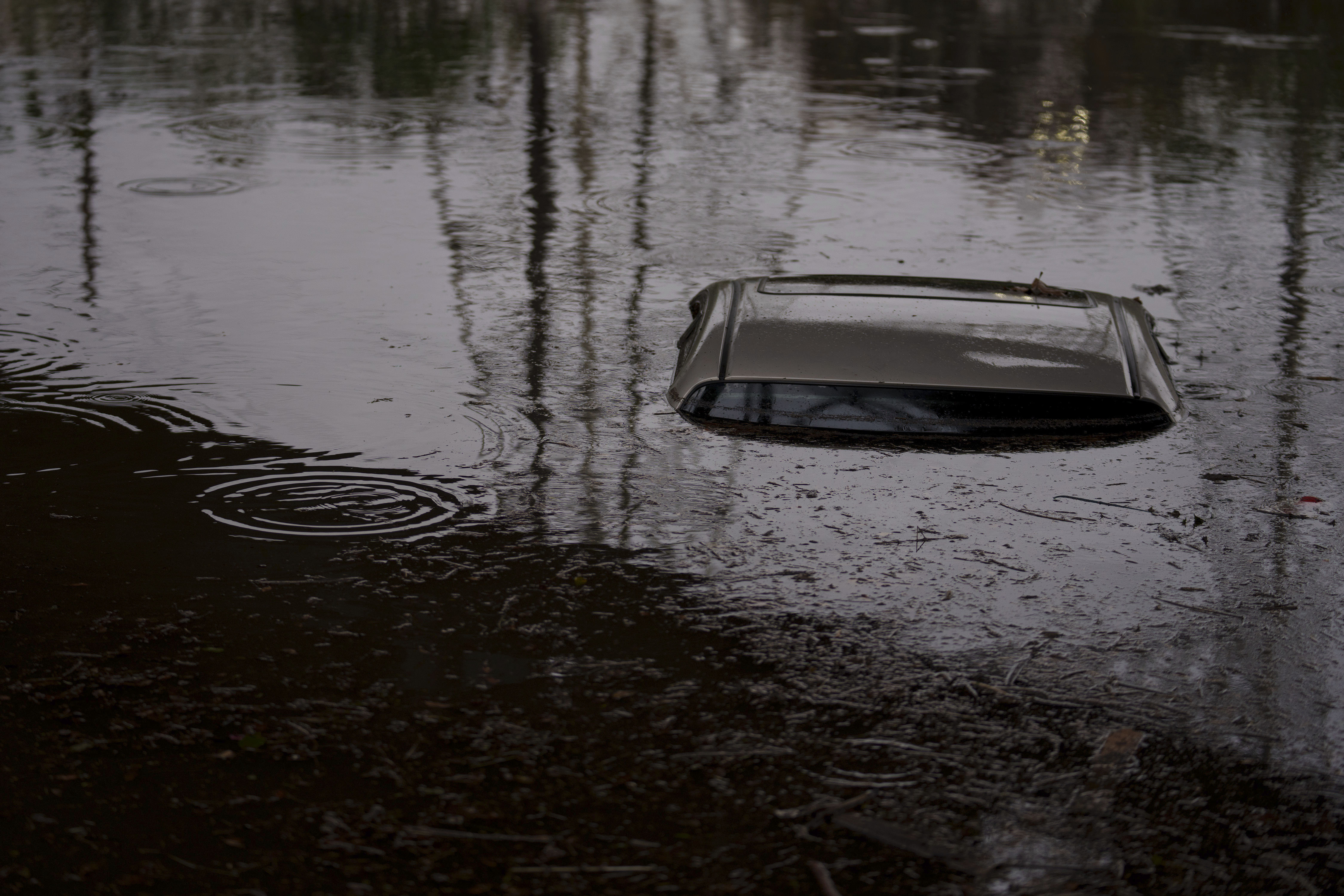 The roof of a submerged car is visible on a flooded street under a railroad bridge, Thursday, Feb. 1, 2024 in Long Beach.