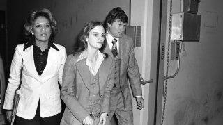 FILE - Accompanied by deputy U.S. Marshal John Brophy, Patricia "Patty" Hearst, center, leaves the Federal building on April 12, 1976, in San Francisco, hours after her sentencing on a bank robbery conviction. The newspaper heiress was kidnapped at gunpoint on Feb. 4, 1974, by the Symbionese Liberation Army, a little-known armed revolutionary group. The 19-year-old college student's infamous abduction in Berkeley, Cali., led to Hearst joining forces with her captors for the 1974 bank robbery. Hearst, granddaughter of wealthy newspaper magnate William Randolph Hearst, will turn 70 on Feb. 20.