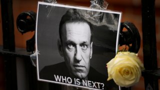 FILE - A flower and a picture are left as a tribute to Russian politician Alexei Navalny, near to the Russian Embassy in London, Feb. 18, 2024. The U.S. government is hitting Russia with the largest tranche of financial penalties imposed on Moscow since its 2022 invasion of Ukraine. They target roughly 600 people and firms from Russia to China to the United Arab Emirates. The sanctions are timed to the second anniversary of the invasion, and in response to the death of Navalny.