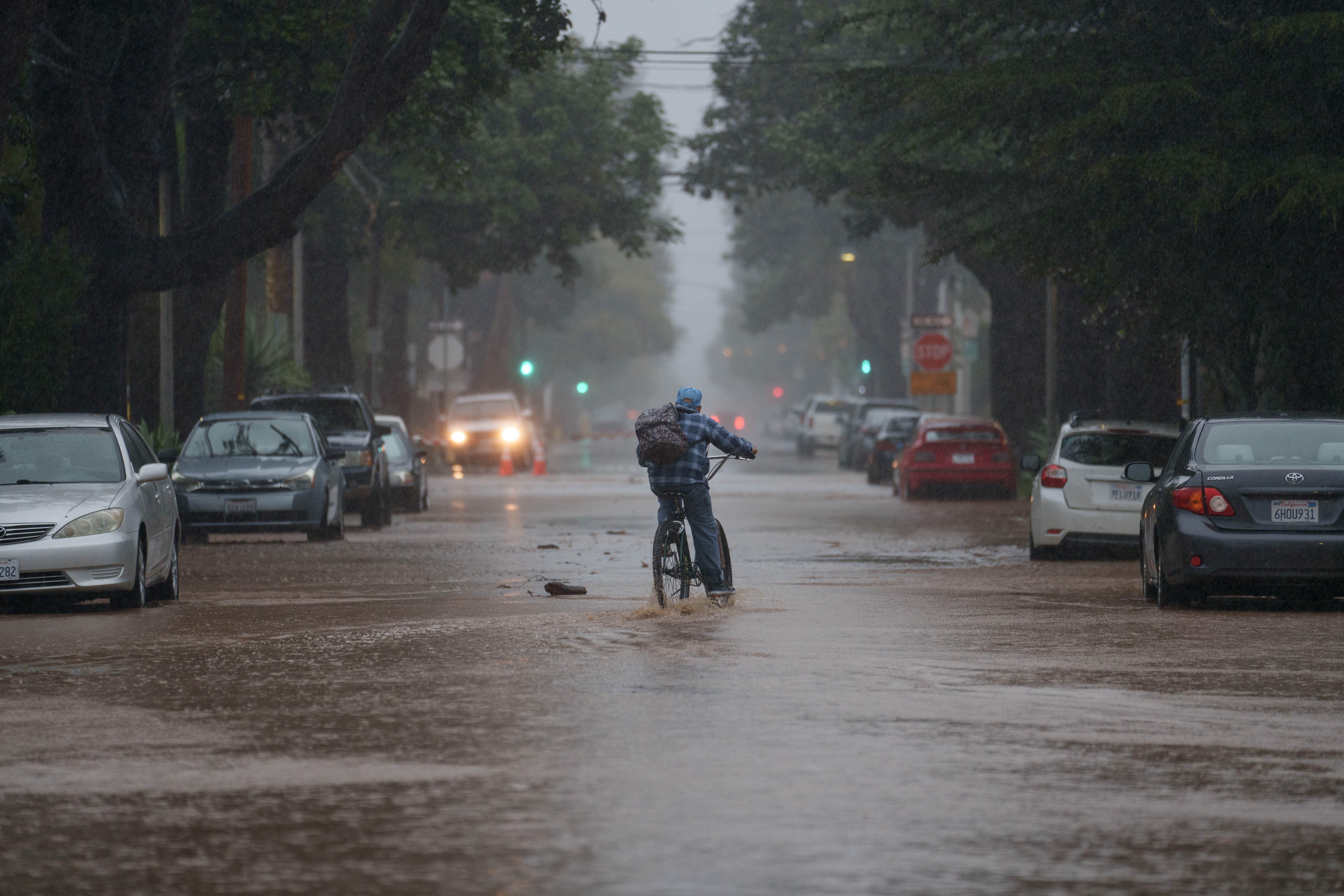 A person rides a bike through floodwater during a storm in Santa Barbara, on Sunday, Feb. 4, 2024. Hurricane-force winds whipped the seas off California, while heavy rains raised flood risks from San Francisco to San Diego, as another powerful Pacific storm arrived on the state’s doorstep.