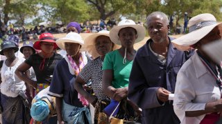 People wait in a queue to receive food aid in Mangwe district in southwestern Zimbabwe