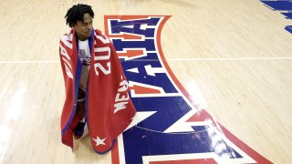 Freed-Hardeman guard Quan Lax wears the championship banner after the NAIA men's national championship college basketball game