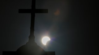 FILE - A partial solar eclipse is seen behind a cross on the steeple of the St. George church, in downtown Beirut, Lebanon, Sunday, June 21, 2020.