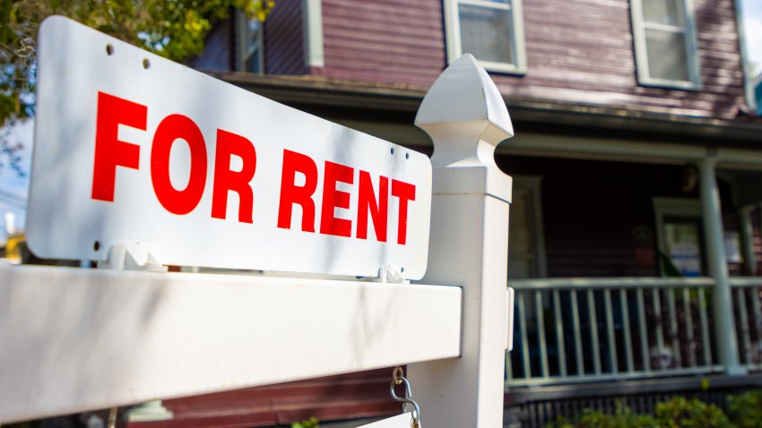 A white and red sign advertises a house for rent.