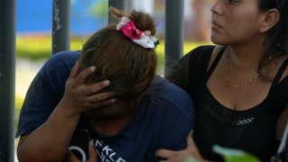 A woman gestures while waiting for the body of one of the victims of the eve shooting