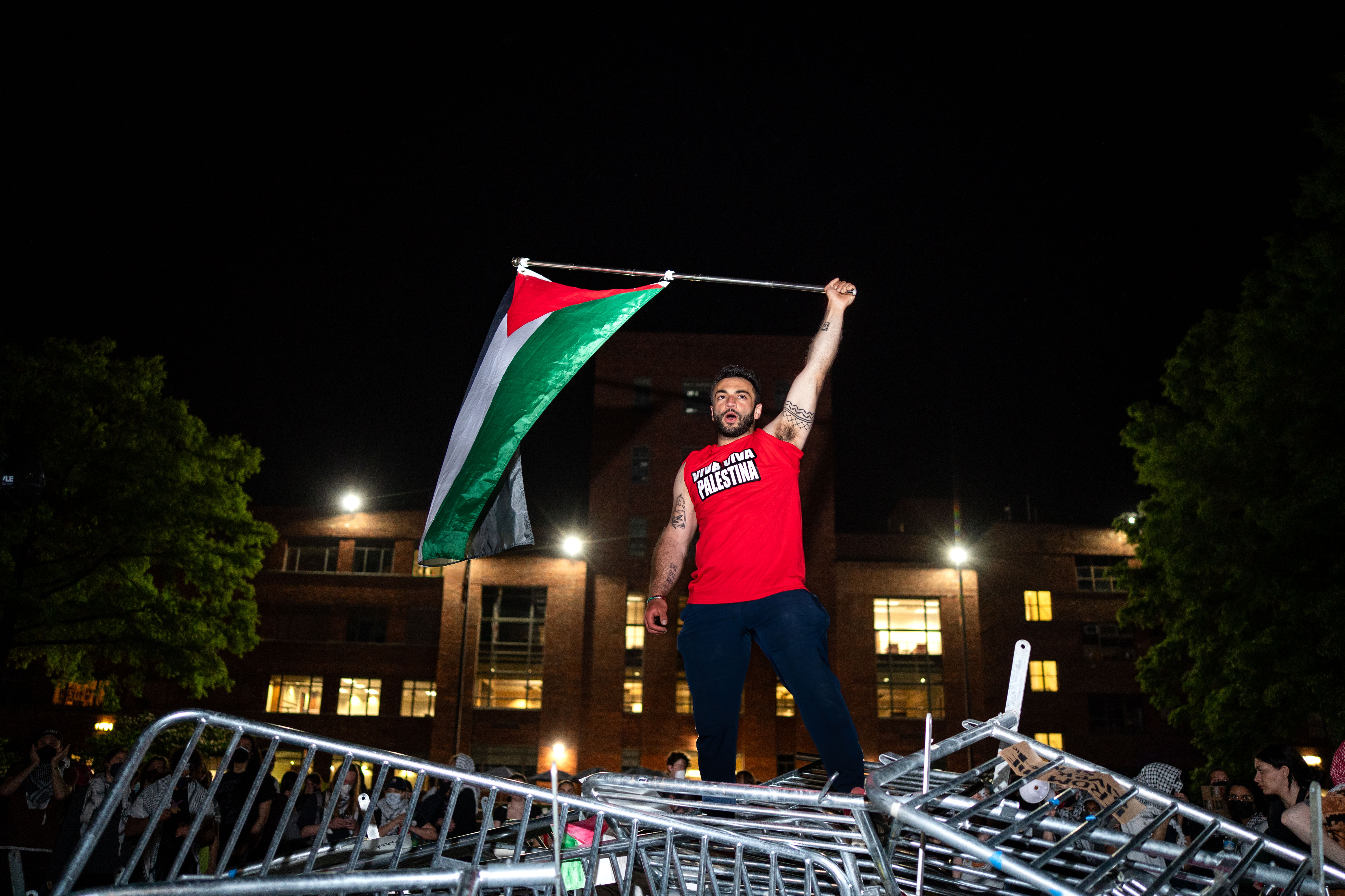 A man holds up a Palestinian flag as activists and students chant at George Washington University on Monday, April 29, 2024 in Washington, D.C.