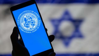 The International Court of Justice displayed on a smartphone, with the flag of Israel visible in the background in Brussels, Belgium, on May 20, 2024.