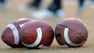 FILE - Footballs stand ready before the Virginia Tech at Wake Forest NCAA college football game in Winston-Salem, N.C., Saturday Oct. 15, 2011. A settlement being discussed in an antitrust lawsuit against the NCAA and major college conferences could cost billions and pave the way for a new compensation model for college athletes.