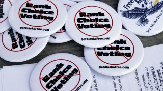 Campaign buttons urging Alaskans to repeal ranked choice voting in Alaska sit on a picnic table at the home of Phil Izon