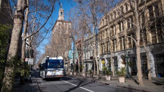 Bus driving down street in Downtown San Jose surrounded by beige buildings
