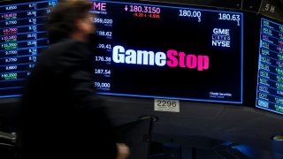 A screen displays the logo and trading information for GameStop on the floor of the New York Stock Exchange.