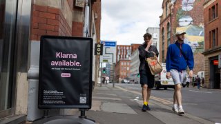 Pedestrians walk by an advertisement for Klarna.