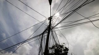 A utility pole with loose cables towers over a home in Loiza, Puerto Rico.