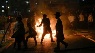 Ultra-Orthodox Jewish men burn trash during a protest against army recruitment