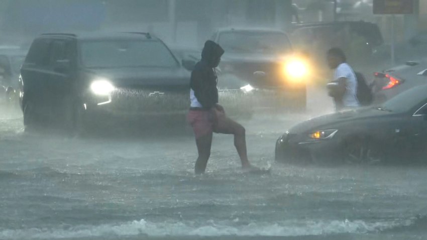 A man wades through flooding on the street