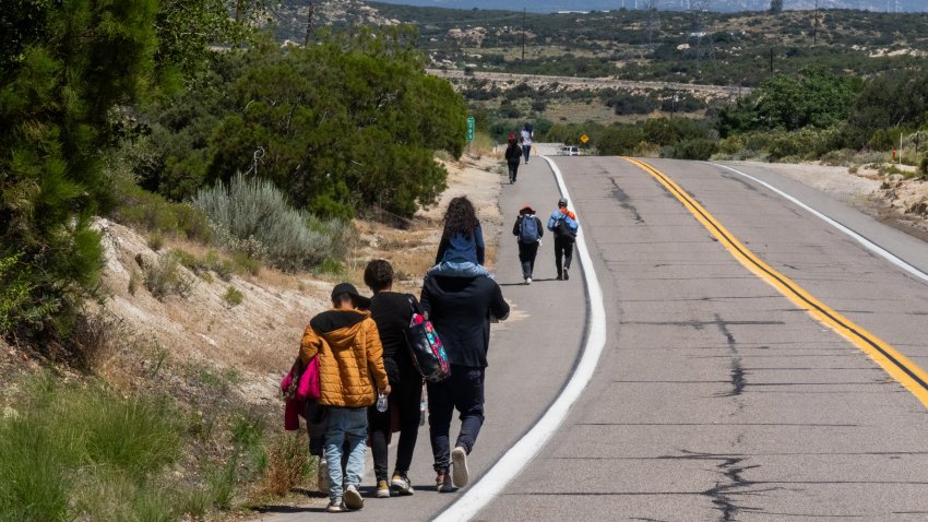 Migrants walk on a long road into the distance