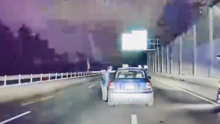 Policia a la orilla de la autopista junto a la ventana de un conductor.