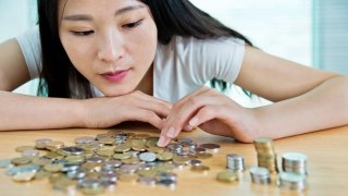 Woman counting a pile of coins.