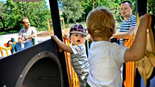 FILE - Henrik Holgersson, right, watches his son, Arvid, center with hat, play with Walter Johansson accompanied by his father Henrik Johansson at a playground in Stockholm, Sweden, Wednesday June 29, 2011.