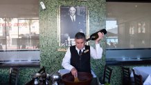 Salad Master Efrain Montoya prepares a Caesar salad in front of an image of the inventor of the salad, Caesar Cardini, at Ceasar's restaurant Thursday, June 27, 2024, in Tijuana, Mexico. Caesar salad has something to celebrate: It's turning 100. Italian immigrant Caesar Cardini is said to have invented the dish on July 4, 1924, at his restaurant, Caesar's Place, in Tijuana, Mexico. (AP Photo/Gregory Bull)