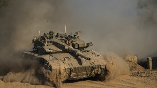 An Israeli soldier moves on the top of a tank near the Israeli-Gaza border, as seen from southern Israel, Sunday, July 14, 2024.