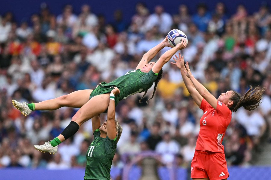 Ireland's Emily Lane (center) catches the ball in a line-out above Ireland's Erin King (down) as challenged by Britain's Lauren Torley (right)