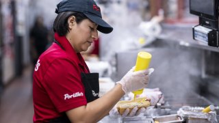 An employee prepares a hot dog at a Portillo’s restaurant in Chicago, Sept. 27, 2022.