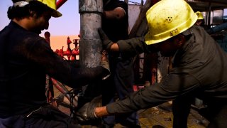 File: A Repsol Oil Operations oil drilling rig pounds into the desert searching through thousands of feet for and oil reserve in El-Sharara, Libya.