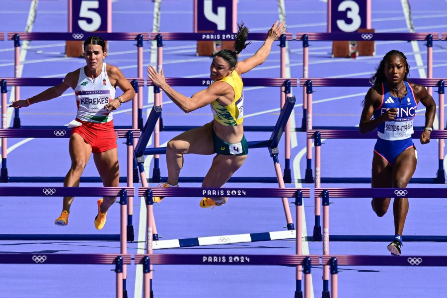 Australia's Michelle Jenneke falls as Hungary's Greta Kerekes and France's Cyrena Samba-Mayela (R) compete in the women's 100m hurdles heat of the athletics event at the Paris 2024 Olympic Games at Stade de France in Saint-Denis, north of Paris, on August 7, 2024