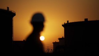 The sun sets beyond crude oil storage tanks at the Juaymah tank farm at Saudi Aramco’s Ras Tanura oil refinery and oil terminal in Ras Tanura, Saudi Arabia, on Monday, Oct. 1, 2018.