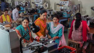 High angle view of female workers showing printed garment to inspector at textile factory