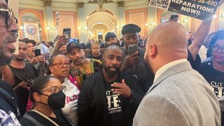 Assemblymember Isaac Bryan, right, talks to members of Coalition for Just and Equitable California  about two  reparations bills in the rotunda on the last day of legislative year, Saturday Aug. 31, 2024 in Sacramento. Calif. (AP Photo/Tran Nguyen)