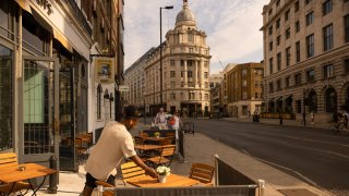 A waiter sets a table in the City of London, UK.