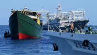 A vessel identified by the Philippine Coast Guard as “Chinese maritime militia” (back R) and a China Coast Guard vessel (front R) sailing near the Philippine military chartered Unaizah May 4 (L) during its supply mission to Second Thomas Shoal in the disputed South China Sea on March 5, 2024. 