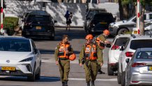 Officers from the Israeli Home Front Command military unit walk on a road near where Israel's government says a drone launched toward Israeli Prime Minister Benjamin Netanyahu's house in Caesarea, Israel, Saturday, Oct. 19, 2024.