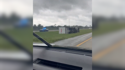 Tornado leaves overturned semi and snapped trees after it passes through I-95